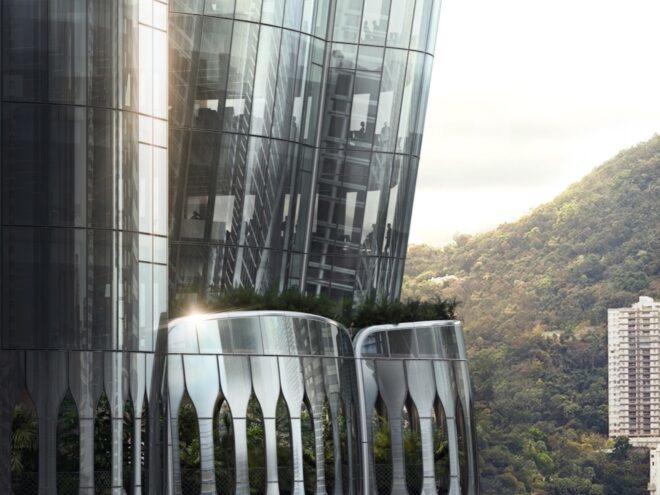 A close-up of the curved glass exterior. In the background, there are trees and hills.