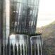 A close-up of the curved glass exterior. In the background, there are trees and hills.