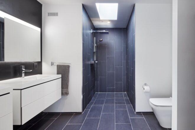 bathroom with white walls and black tiles