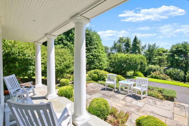 large front porch with white columns facing lush yard