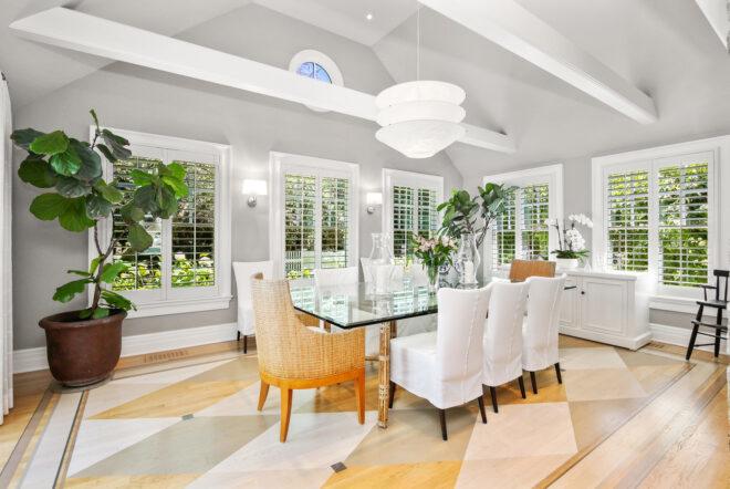 long glass dining table in gray room with several windows and tall ceilings