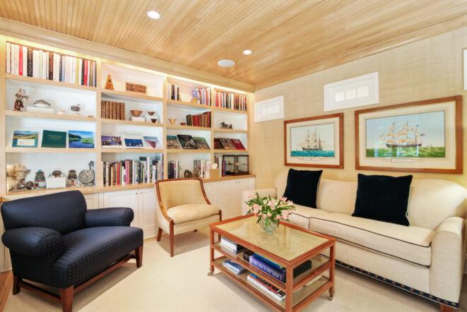 den with white sofa, beige chair, blue chair and a wall of bookshelves
