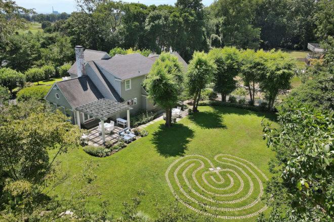 aerial view of white home with gray roof surrounded by trees