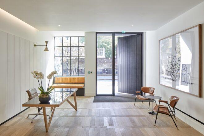 apartment with white walls, large black front door, and minimalist furniture