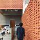 person walking past perforated red wall