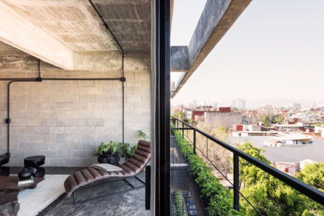 white lounge chair near wall of glass with small balcony