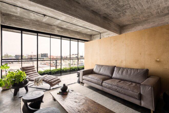gray sofa and white lounge chair near wall of glass