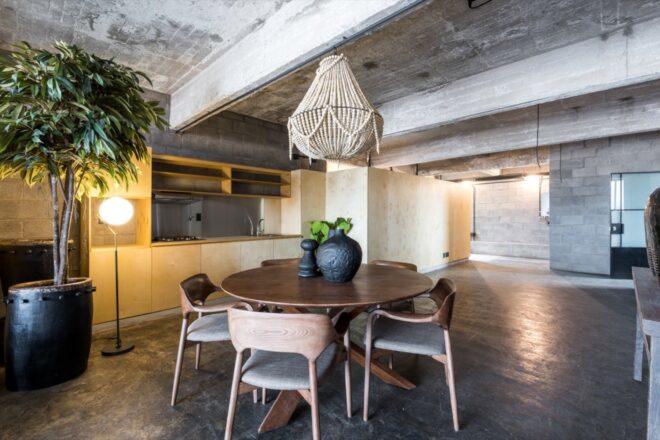 round wood table under chandelier in industrial building