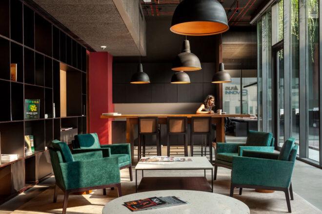 a sitting area with four green armchairs surrounding a white square coffee table.