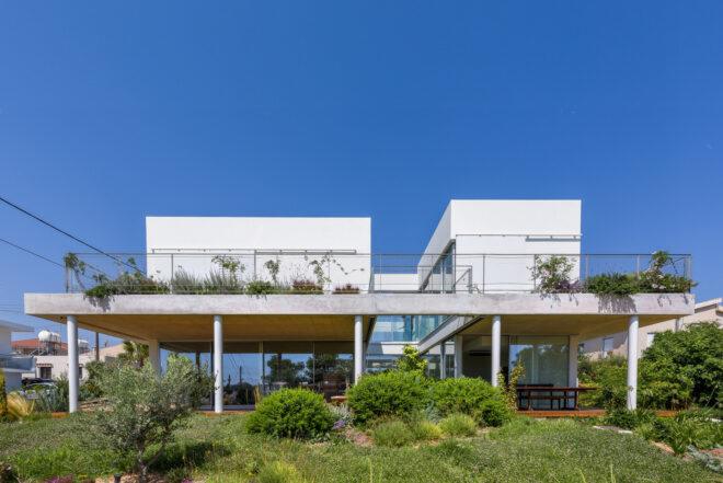 large white home with plant-covered balcony