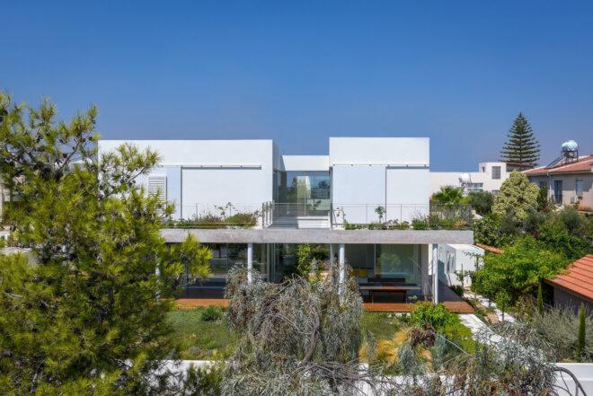 plants covering ground floor and upper balcony of a white home
