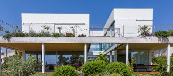 large white home with plant-covered balcony