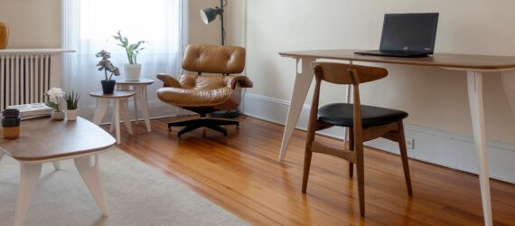 a living room with a coffee table, leather armchair and desk table with wood chair.