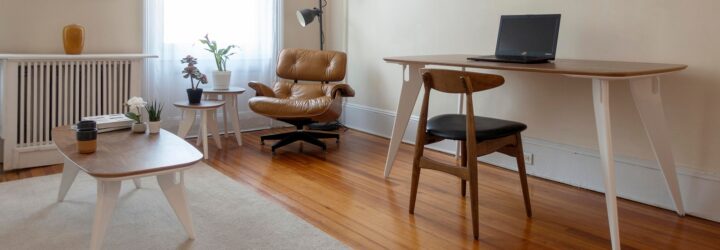 a living room with a coffee table, leather armchair and desk table with wood chair.