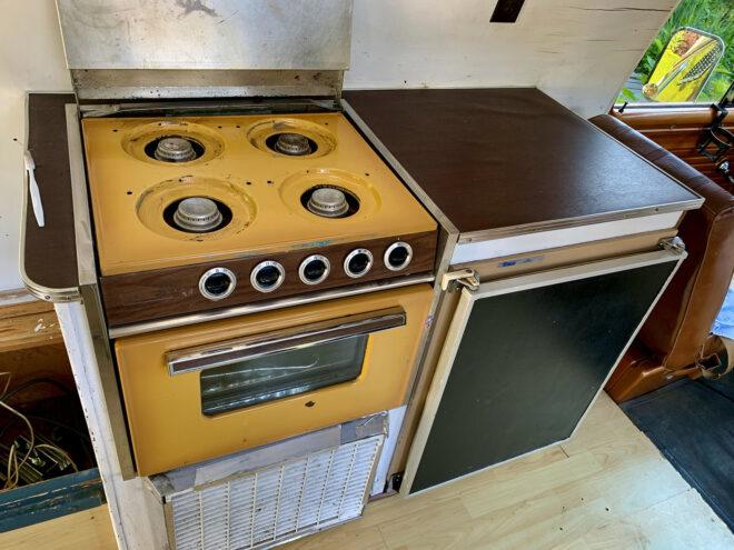 a yellow stovetop in disrepair before being renovated.