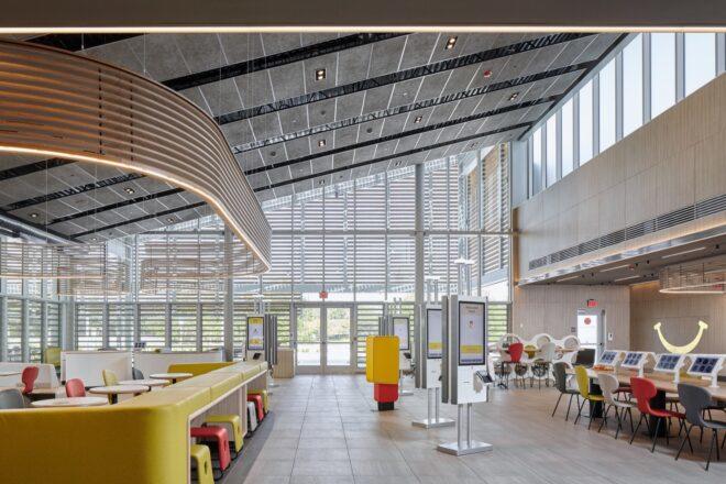 a view of the interior of the McDonald's with white industrial designs and lightbulbs hanging from the ceiling. the sloped roof design shows, elevating from left to right.