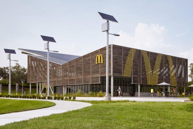 a side view of a McDonald's restaurant with a sloped, v-shaped roof. free-standing solar panels surround the building.