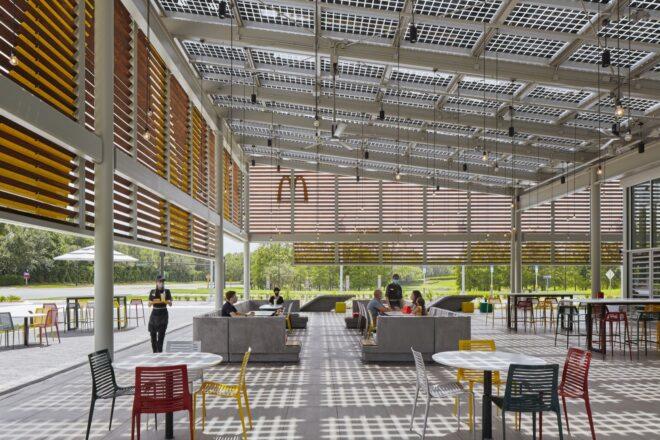 a view of the interior of the McDonald's with white industrial designs and lightbulbs hanging from the ceiling. the sloped roof design shows, elevating from right to left.