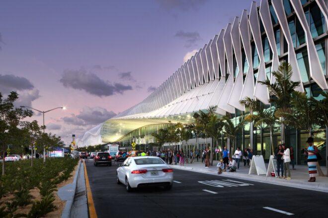 car driving past metal and glass building with several solar fins