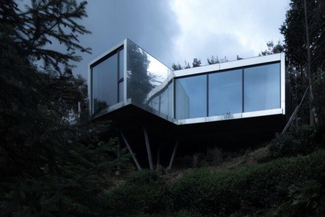 reflective metal and glass cabin on hillside