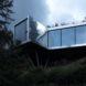 reflective metal and glass cabin on hillside