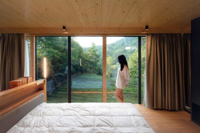 person standing beside bed and looking out window