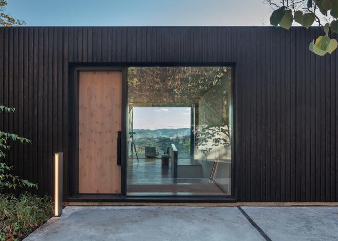 a building with a dark timber facade and a light-colored wood door next to a window.