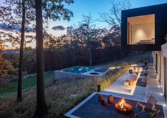 a backyard with fire pit and chairs, a pool and lounge chairs.