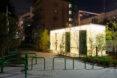 glowing white public toilet building with green doors