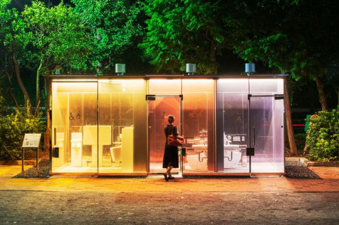 public toilet building with yellow, red and purple glass walls that are transparent with doors open