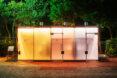 public toilet building with yellow, red and purple glass walls that are opaque with doors closed