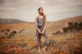 person in gray tank top and gray pants standing in a field of poppies