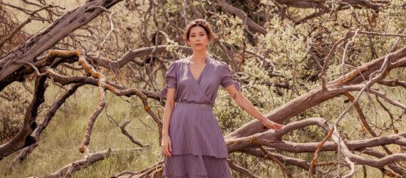 person in gray dress standing beside a tree