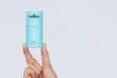 a hand holding a blue tube of deodorant.