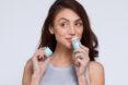 a person holding the top of a deodorant tube in one hand and the tube itself in the other hand. the tube is raised to the person's nose.