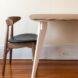 a wood chair with clack seat next to a table with a wood top and white legs