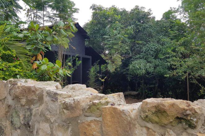black gabled home surrounded by trees and a stone wall