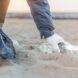gloved hand picking up trash on a beach