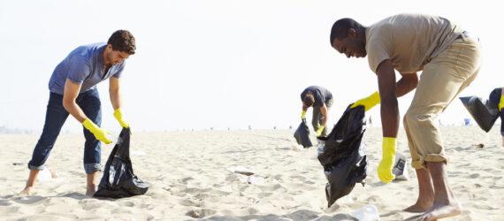 group of volunteers picking up trash on a beach