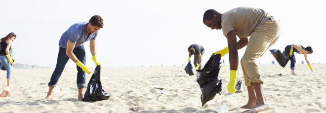 group of volunteers picking up trash on a beach