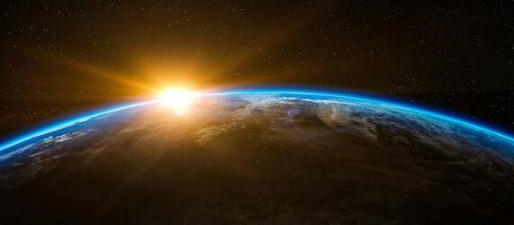 sun rising over Earth in space
