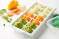 a white ice tray filled with green, orange and white baby food.
