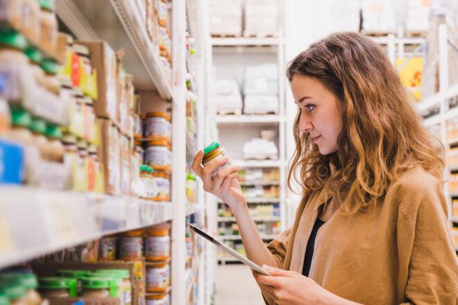 a person standing in the baby food aisle at a store, holding a jar of baby food.