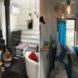 On the left, white chair in small living area. On the right, blue and white bedroom.