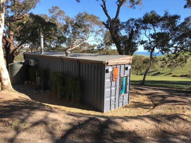 black corrugated metal tiny home facing hilly landscape