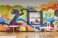 tables and chairs in room with colorful wall mural