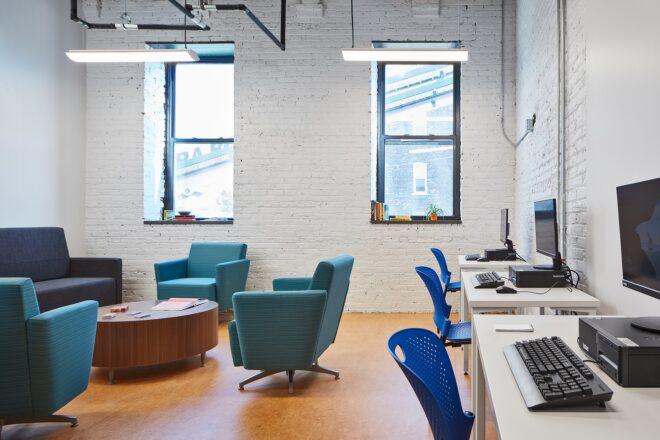 meeting room with white brick walls and computers on wood desks