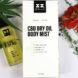 A bottle of CBD body mist next to a white packaging box and a red flower.