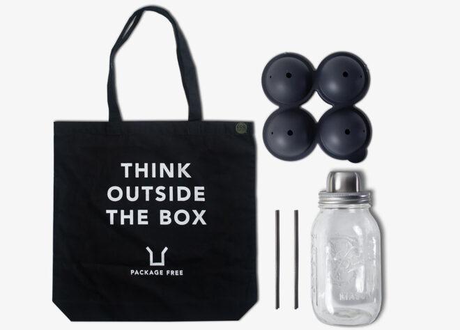 A black tote bag reading "Think outside the box," a set of four ball ice molds, two metal straws and a mason jar shaker.