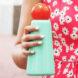 A hand holding a retro cyan and red water bottle.